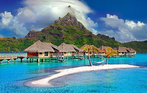 Why make money with a laptop. showing an image of a beautiful island with huts on docks over the water.