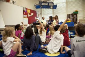 Kids in a classroom raising their hands