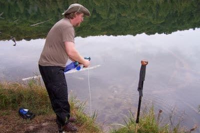 Hiker filtering water from a lake.