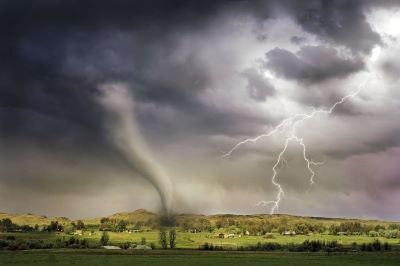 Tornado touching down in a field with lightening